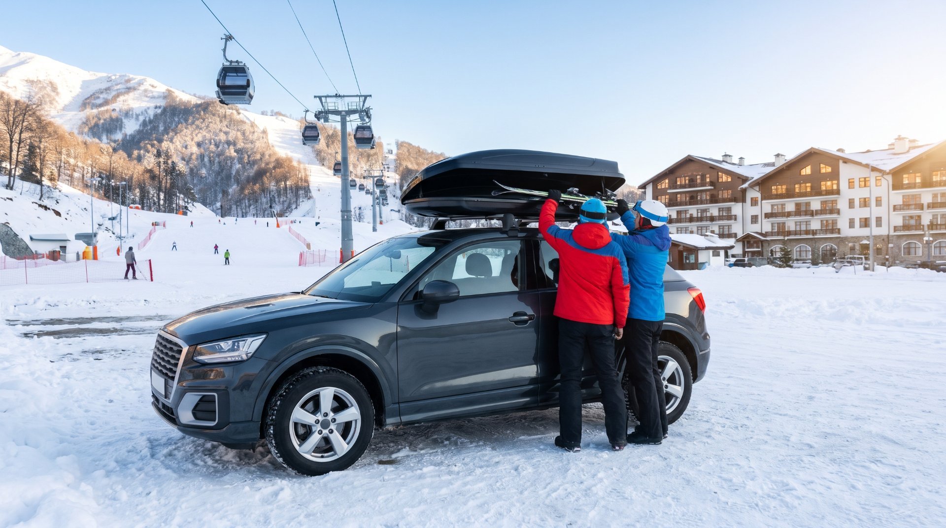 Couple loading skis into an SUV roof box at a ski resort car park